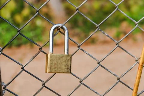 A sturdy padlock securing a chain link gate, symbolizing safety, restrictio.. Stock Photos