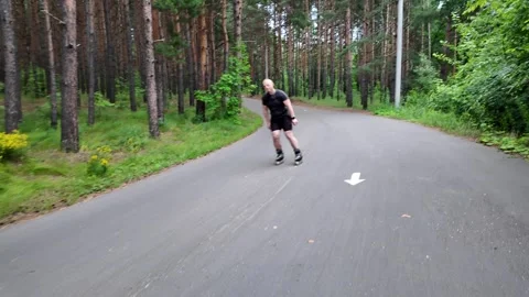 Sturdy roller skater races down mountain path in forest at sunset Stock Footage 341817055