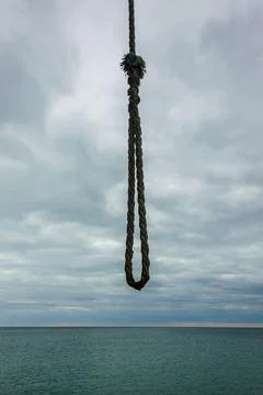A sturdy rope loop hangs against a serene ocean horizon. The sky and the se.. Foto stock