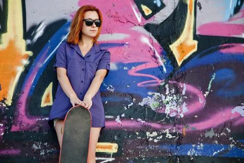Style girl with skateboard near graffiti wall. Stock Photos