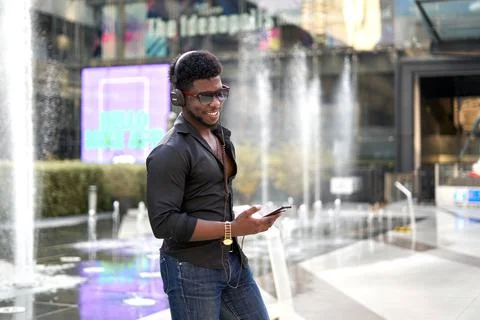 Stylish african man smiling while listening to music with a mobile outdoors Stock Photos