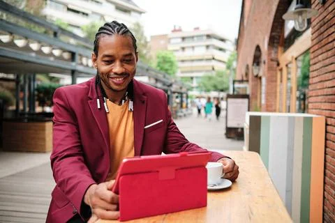 Stylish african man using a tablet in a cafeteria Stock Photos
