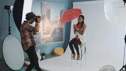 Stylish african model posing with red umbrella on bar high chair for fashion Stock Footage 122585115