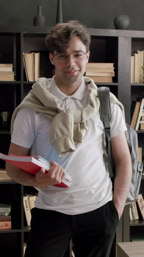 Stylish and handsome student with backpack on his back and books in his hands Stock Footage 316603379