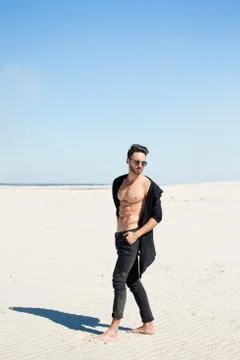 Stylish, athletic guy on the background of sand Stock Photos