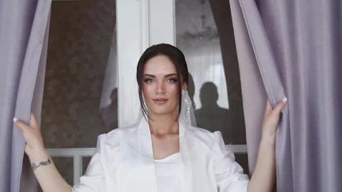 Stylish attractive bride is opening the curtains. Front close up view. Stock Footage 243661213