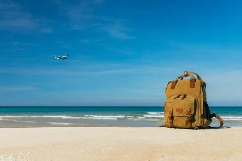 Stylish backpack on a snow-white empty beach by the sea, with an airplane Stock Photos