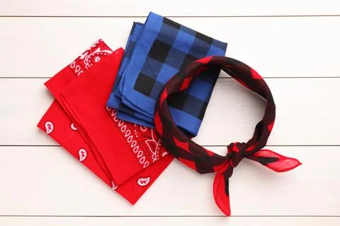 Stylish bandanas with different patterns on white wooden table, flat lay Stock Photos