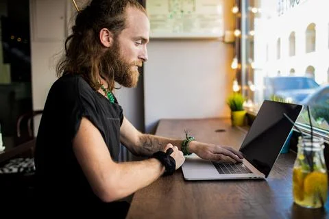 Stylish bearded hipster guy using laptop computer for distance work in intern Stock Photos