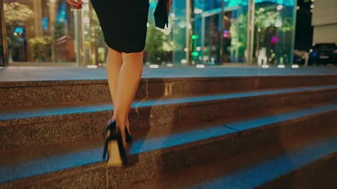 A stylish beautiful young girl in a black dress walks through the night city Stock Footage