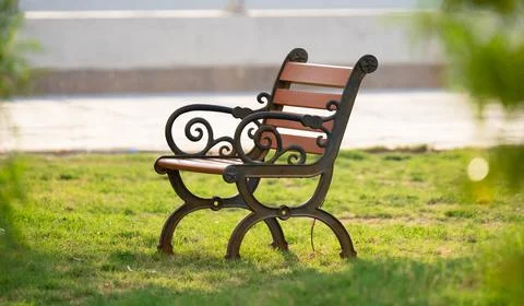 Stylish bench at a park between trees. Stock Photos