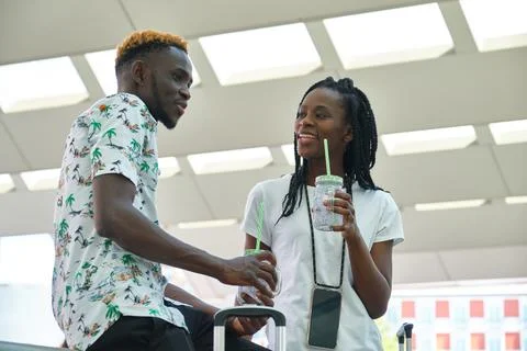 Stylish black couple drinking refreshing drinks and talking at street Foto stock