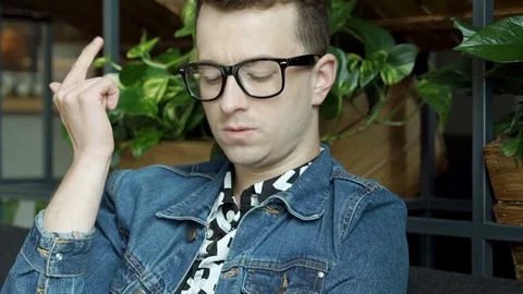 Stylish boy in glasses sitting in the cafe and counting something on fingers, st Vídeos de archivo 79377970