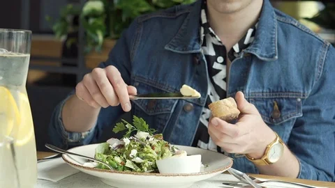 Stylish boy sitting in the cafe and spreads butter on bread, steadycam shot 스톡 동영상 79362795