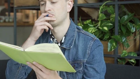 Stylish boy thinking while writing something in his notebook, steadycam shot Stock Footage 79363527