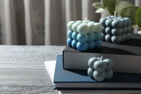 Stylish bubble candles and stack of books on grey wooden table, closeup. Sp.. Foto stock