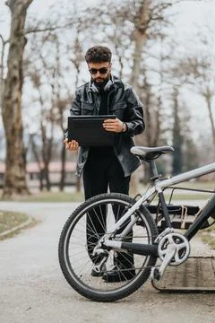 Stylish businessman with tablet outdoors checking email by his bike Foto stock