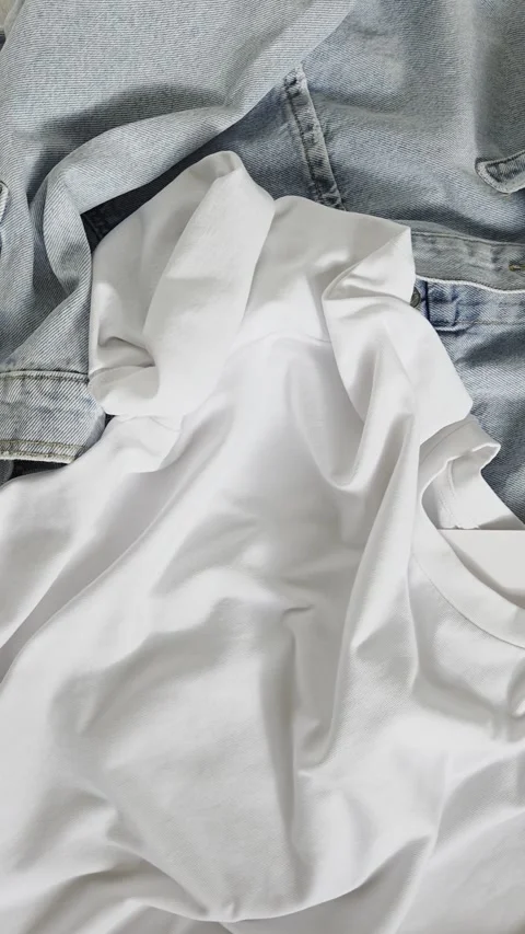 Stylish casual clothes top view close up. Fashion t-shirt mockup with label, jea Stock Footage 340842370