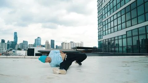 Stylish caucasian dancing man performing break dance at skyscraper. Hiphop. Stock Photos