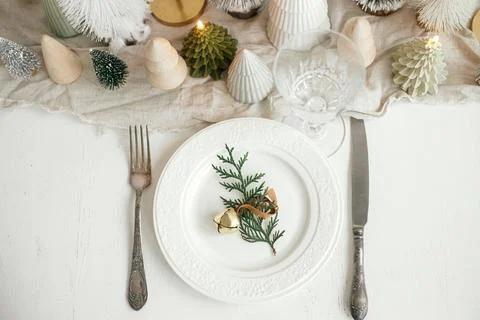 Stylish Christmas table setting. Cedar branch with bell on plate, cutlery, .. Stock Photos
