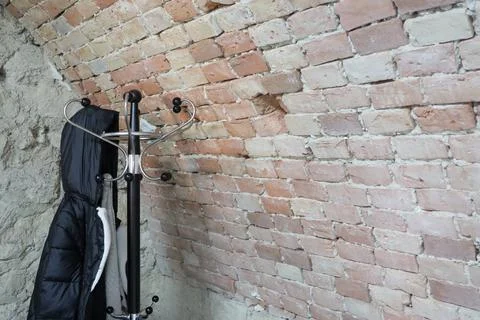 A stylish coat rack designed elegantly by a beautifully textured brick wall Stock Photos