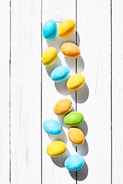 Stylish colorful easter eggs on white wooden background. Happy Easter. Gree.. Stock Photos