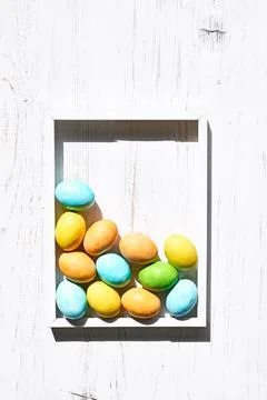 Stylish colorful easter eggs in white frame on white wooden background. Hap.. Stock Photos