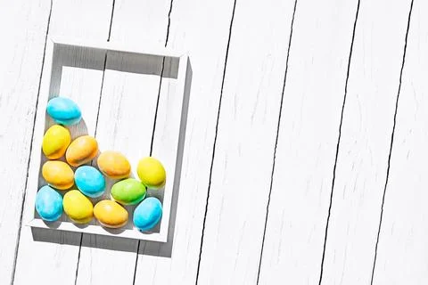 Stylish colorful easter eggs in white frame on white wooden background. Hap.. Stock Photos