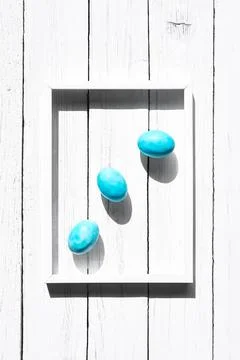 Stylish colorful easter eggs in white frame on white wooden background. Hap.. Stock Photos