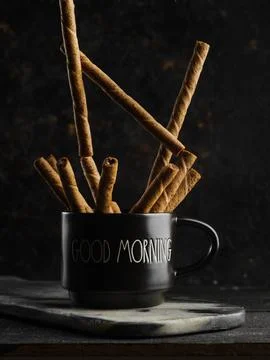 Stylish composition. On a black background, a black cup with fragrant cinnamo Stock Photos
