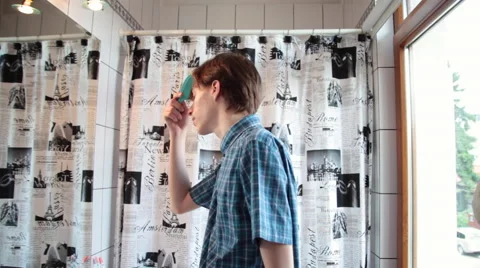 Stylish confident young man looking in a mirror and combing his blonde hair Stock Footage 51677214