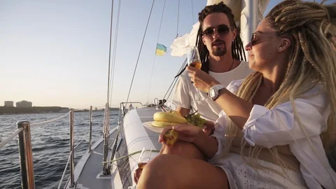Stylish couple with dreadlocks in white clothes and sunglasses sitting embracing Stock Footage 119072851
