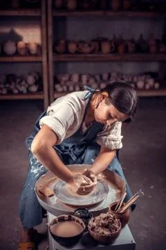 Stylish craftsman demonstrates the process of making ceramic dishes using the Stock Photos