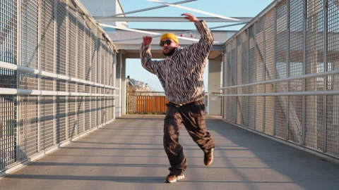 Stylish dancer male in zebra-patterned hoodie and beanie performs Stock Footage 292552404