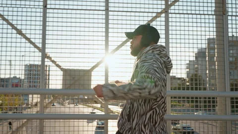 Stylish dancer male in zebra-patterned hoodie and beanie performs Stock Footage 292565994