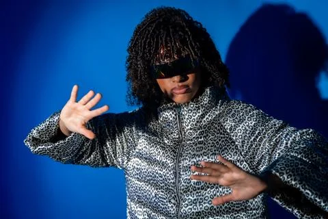 Stylish dancer moving with hands up on blue background 스톡 사진