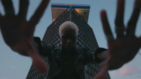 Stylish Dark Skinned Guy On Evening City Street. Behind Him Is High Rise Video stock 212469013