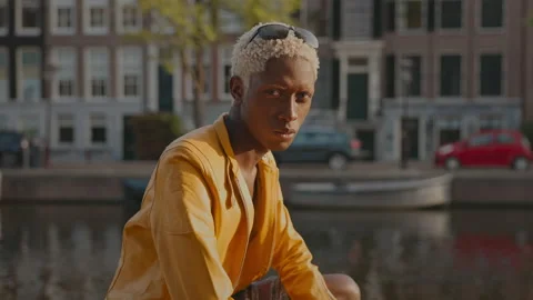 Stylish Dark Skinned Guy On Street. He Sits On Boat. Stock Footage 210189802