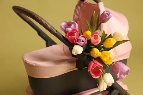 Stylish doll stroller and tulips on olive background. Kid's toy Photos