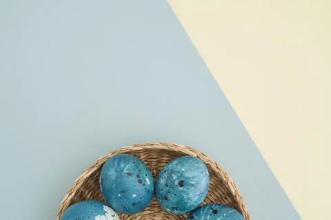 Stylish easter composition with blue easter eggs in a basket on a yellow-blue Stock Photos