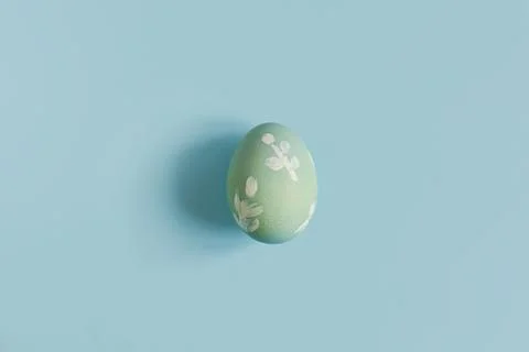 Stylish easter egg on blue background flat lay. Minimal Easter still life. .. Stock Photos
