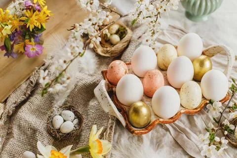 Stylish easter eggs and blooming spring flowers on rustic fabric background.. Stock Photos