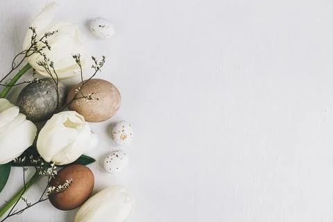 Stylish Easter eggs and tulips border on rustic white wooden background, fl.. Stock Photos