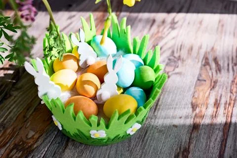 Stylish easter eggs with bunny in green nest on wooden table in the sunny d.. Stock Photos