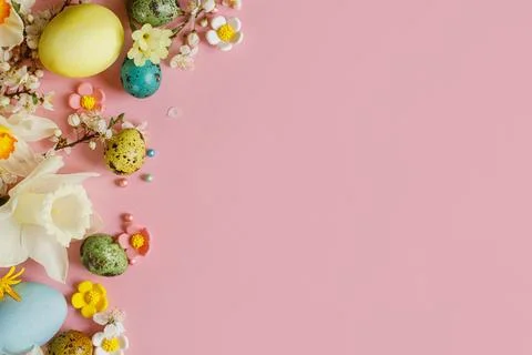 Stylish easter eggs, candy and blooming flowers on pink background flat lay.. Stock Photos