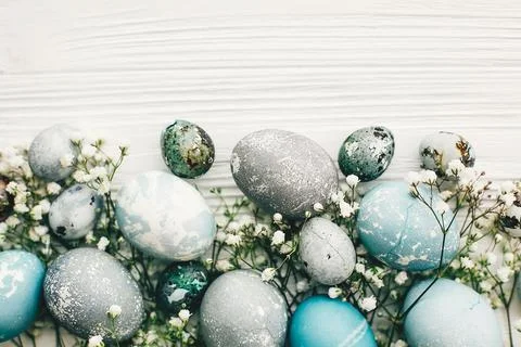 Stylish easter eggs with spring flowers on white wooden background with spa.. Stock Photos