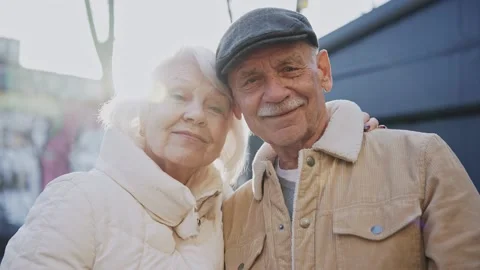 A stylish elderly couple smiling at camera standing on a sunny modern street Vídeo Stock 178949856