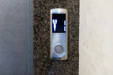 A stylish elevator control panel features a digital display, glowing with b.. Stock-Fotos