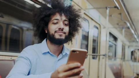 Stylish Expressive Curly Dark-Skinned Man Sitting in Subway Wagon with Stock Footage 136069235