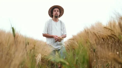 Stylish farmer of Caucasian appearance with a hat and beard walks in the field Stockbeeldmateriaal 134036367